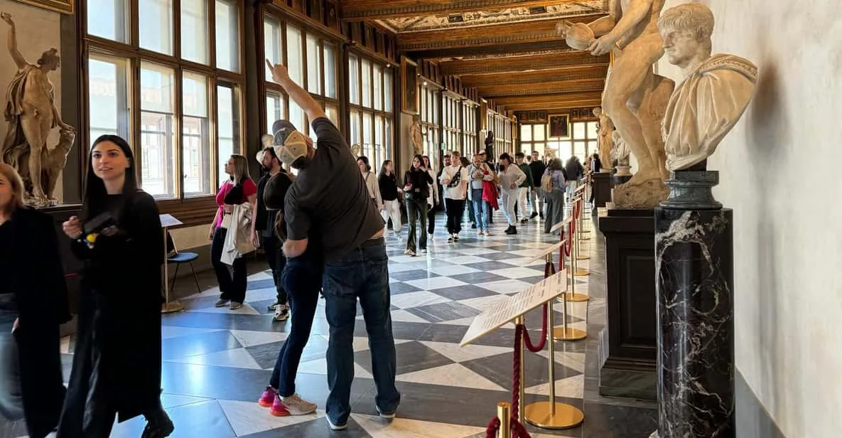 Visitors in the vaulted Uffizi Gallery corridor lined with sculpture, one of the top museums in Florence, Italy